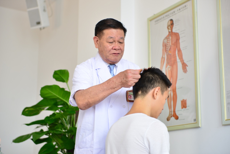 国医大师黄瑾明为患者进行壮医药线点灸疗法治疗。taptap点点体育供图